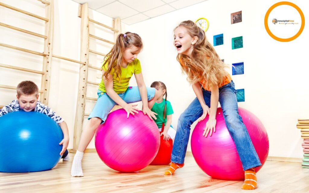 Four children having fun with gymnastic balls.
