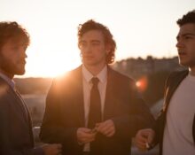 Three men are showing off their suits.