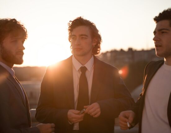 Three men are showing off their suits.